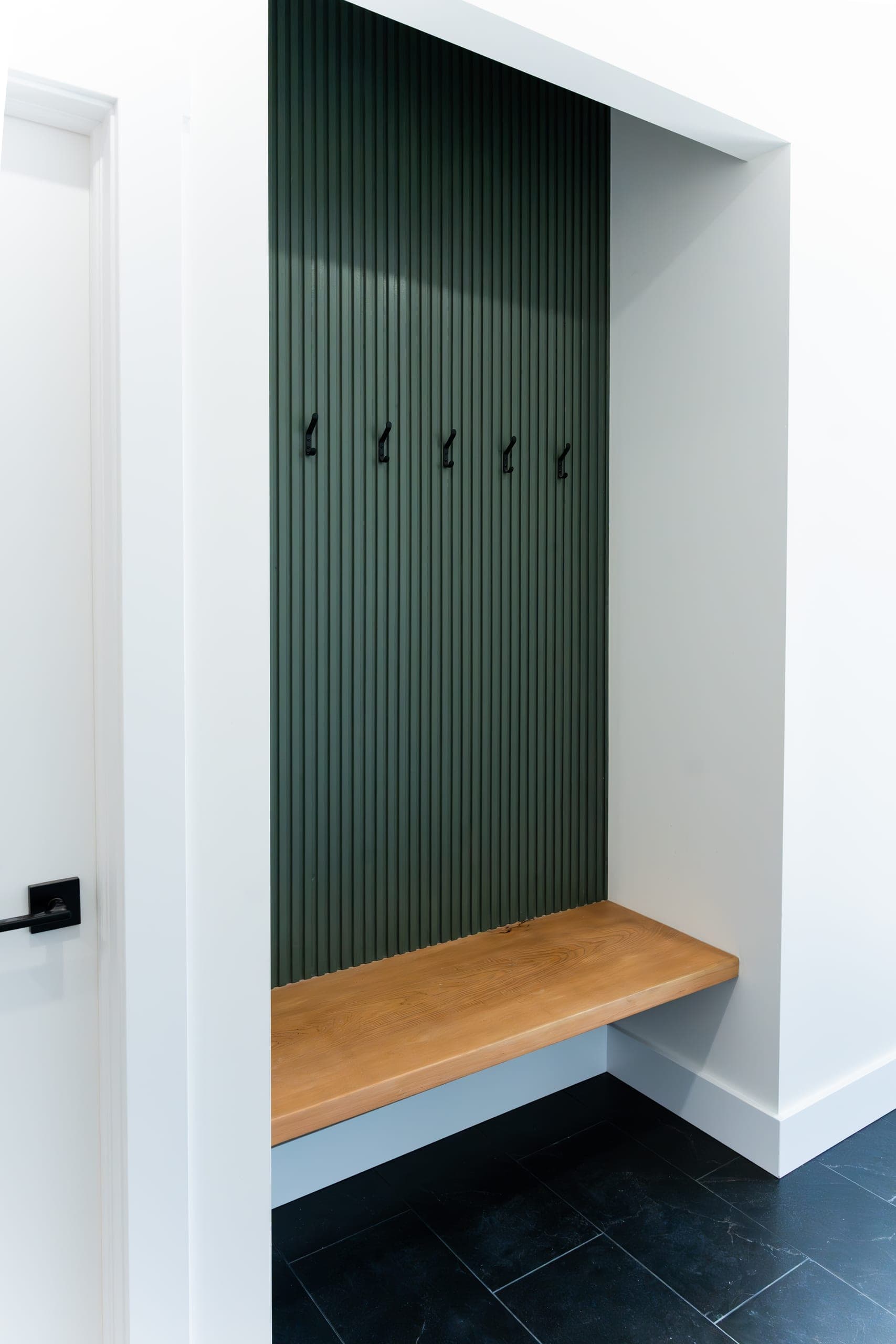 Custom mudroom millwork — fluted green panel and bench
